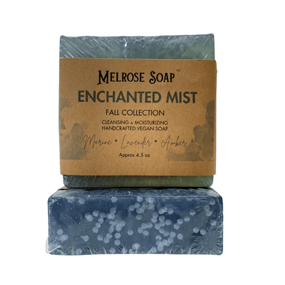 Enchanted Mist handcrafted vegan soap bars from Melrose Soap Fall Collection, labeled bar with marine, lavender, amber scent and second bar showing blue swirl design with white bio-glitter, approx. 4.5 oz.